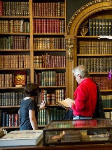 Two people browse a wall of leather bound books